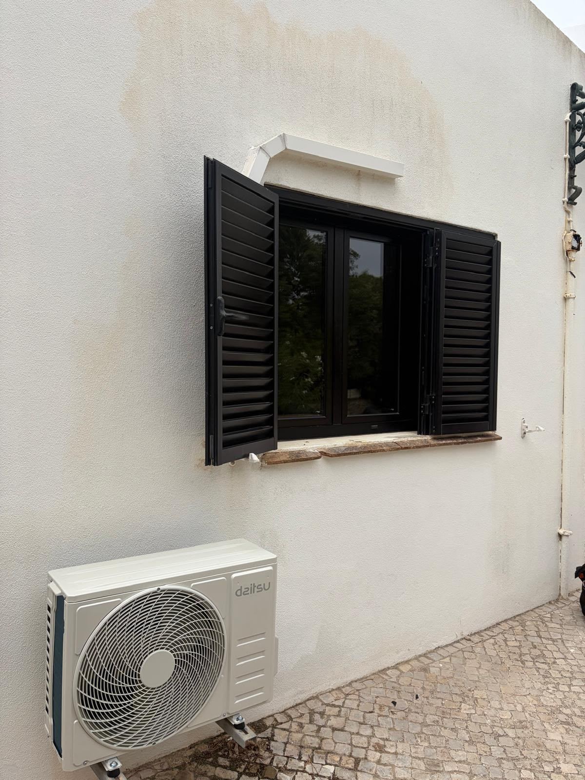 Daitsu outdoor unit by a shuttered window
